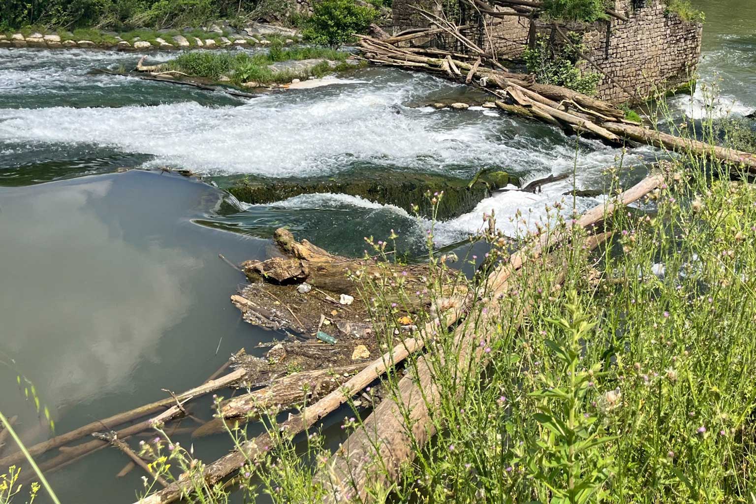 Resti di antiche strutture idrauliche sul corso del fiume, parzialmente ostruite da materiale legnoso trasportato dalla corrente: area oggetto di intervento di monitoraggio e rimozione selettiva degli ostacoli naturali per prevenire allagamenti e migliorare il deflusso.